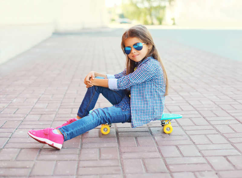 漂亮小女孩坐在滑板上