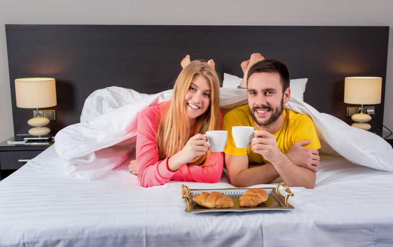床上喝咖啡吃早餐的夫妇