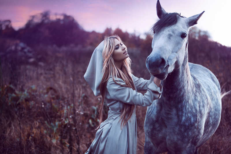 户外草甸间的美女模特和马