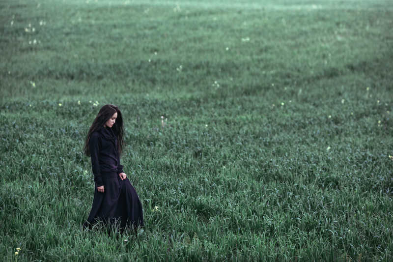 户外黑发女孩在草地上行走