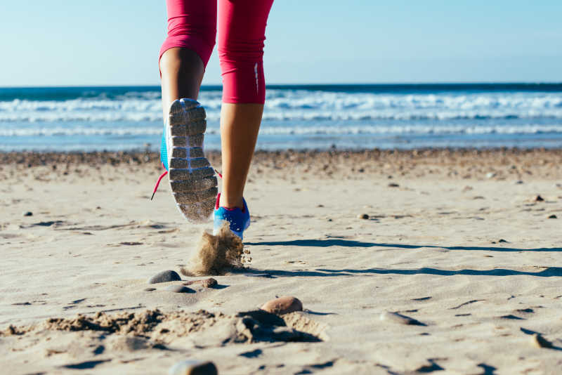 在沙滩上奔跑的女子足部特写