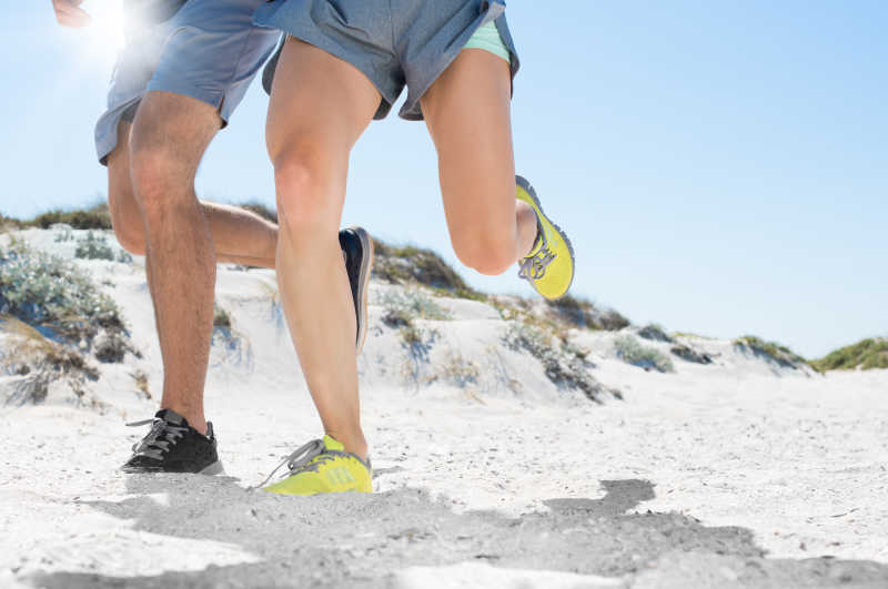 沙滩上跑步健身的夫妇腿部特写