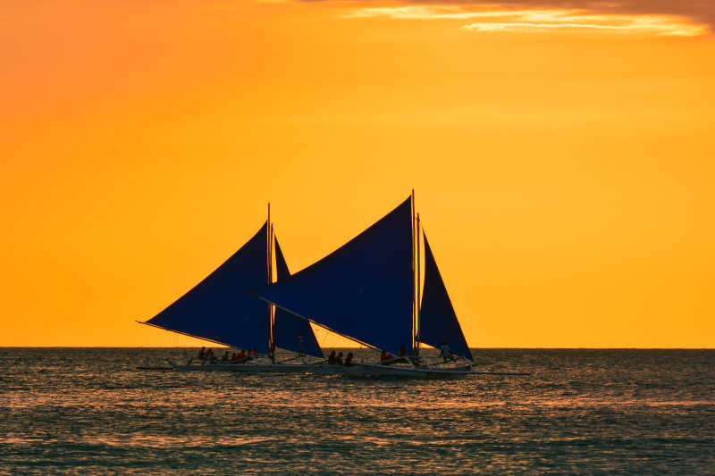 日落时分行驶在大海里的两只帆船