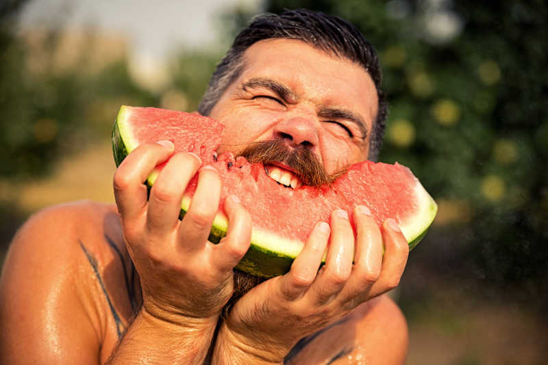 长着胡子的中年男性在吃西瓜