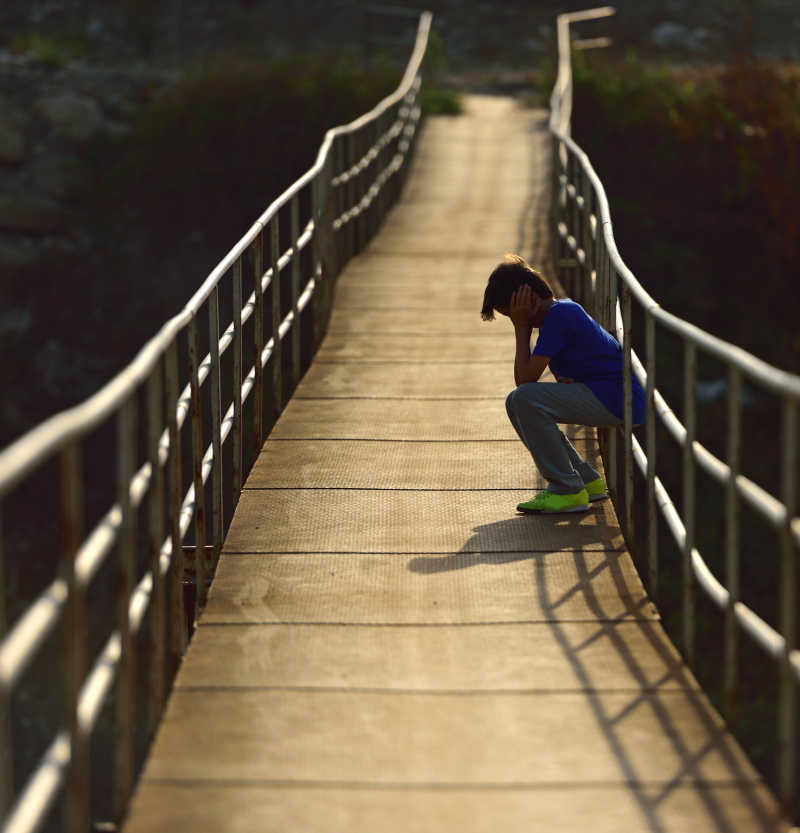 孤独的坐在桥上的小男孩