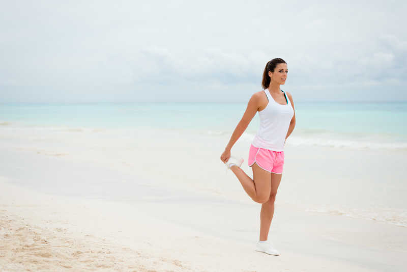 在沙滩上做腿部伸展运动的健康美女