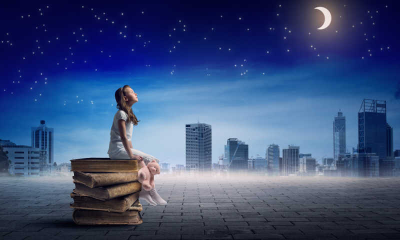 月光下坐在书上的小女孩