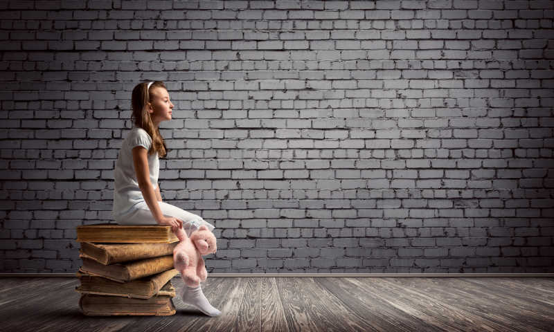 一个可爱的小女孩坐在一堆书上
