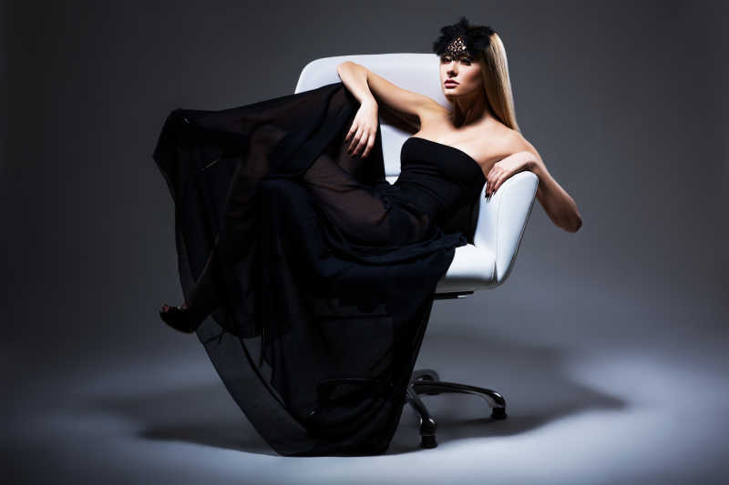 坐在白色椅子上的穿着黑色连衣裙的美女