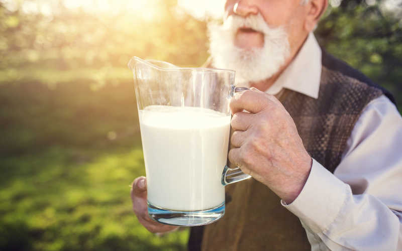 果园里拿着一杯牛奶的老人
