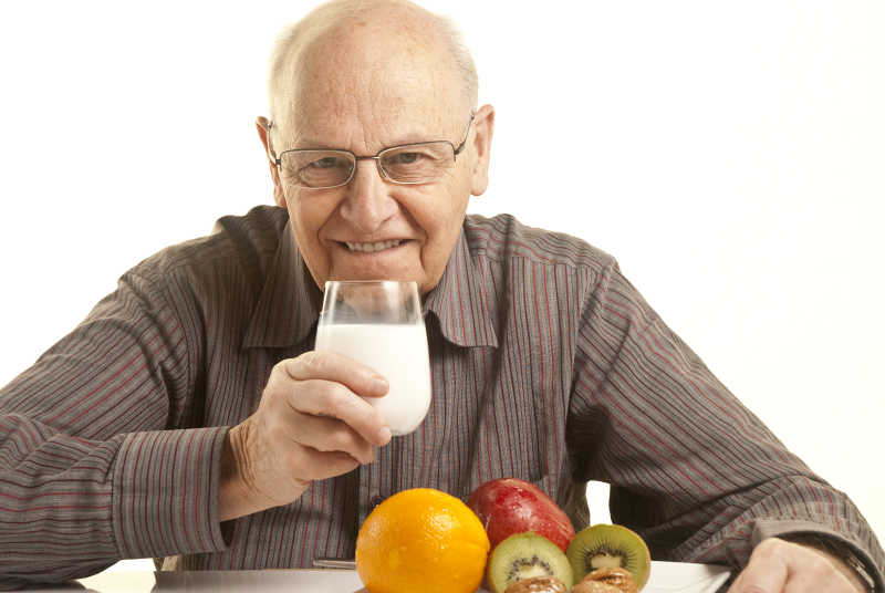 吃早餐的老人手里端着一杯牛奶