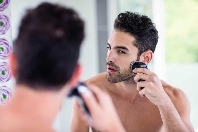 男人对着镜子刮胡子