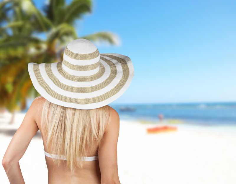 沙滩上戴着太阳帽的金发比基尼美女