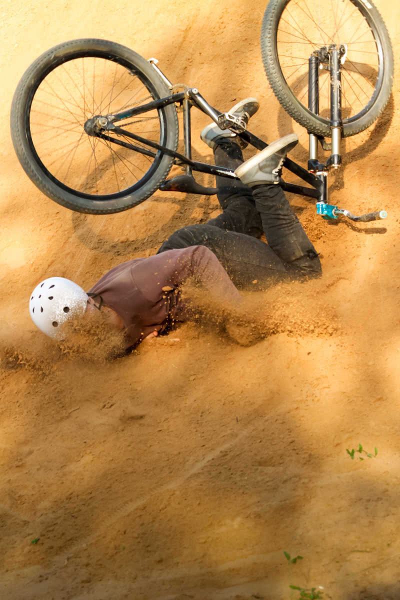 骑自行车的人从他的山地自行车倒在沙