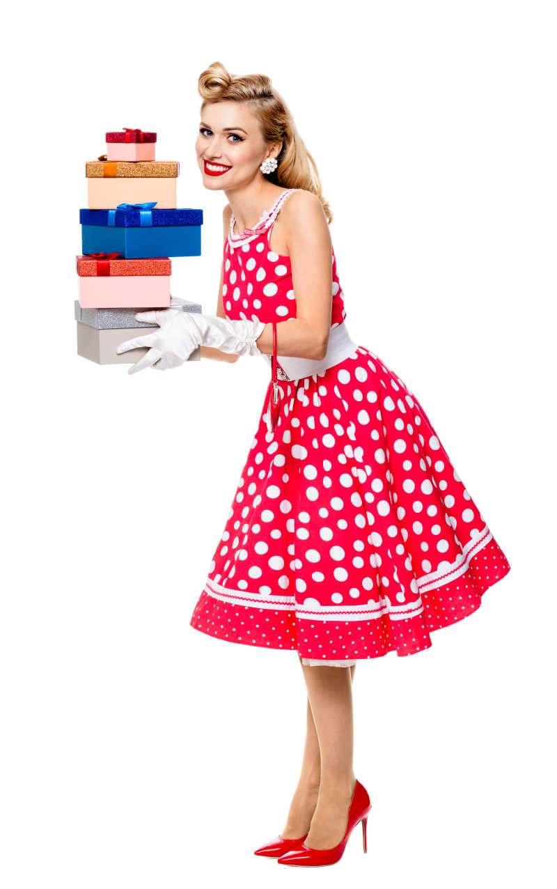 带着白色手套穿着圆点式的红色礼服的美女抱着一摞礼品盒