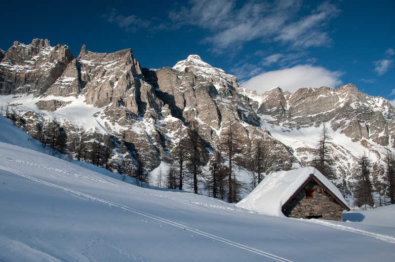 山区岩石下雪天的小屋