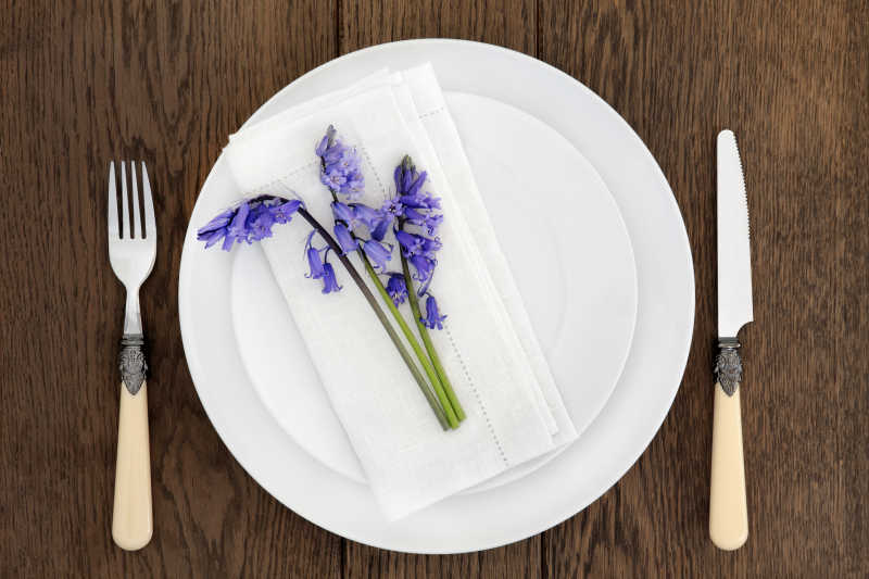 棕色木质桌面上的餐具和蓝色花朵