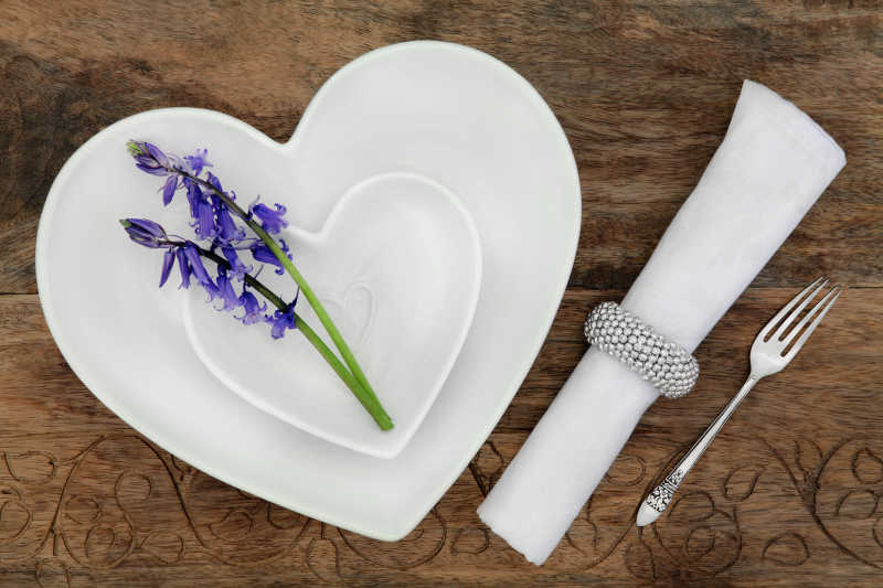木桌上心形餐具上的紫色风铃花