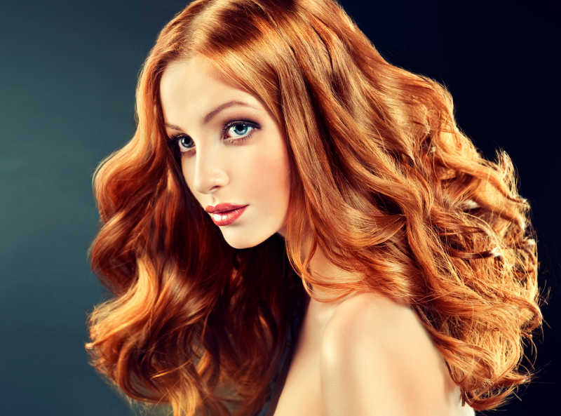 美丽的模特留着长长的红色卷发