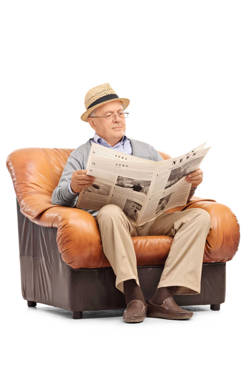 在扶手沙发上看报纸的老人