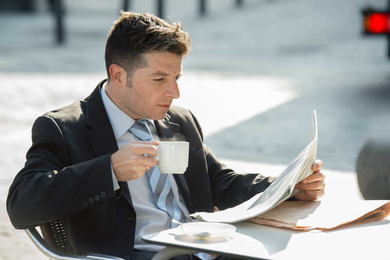 早餐喝咖啡杯看报纸的年轻魅力男商人