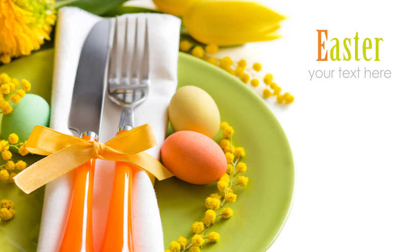 白色背景下复活节餐桌上的黄色花餐具和彩蛋