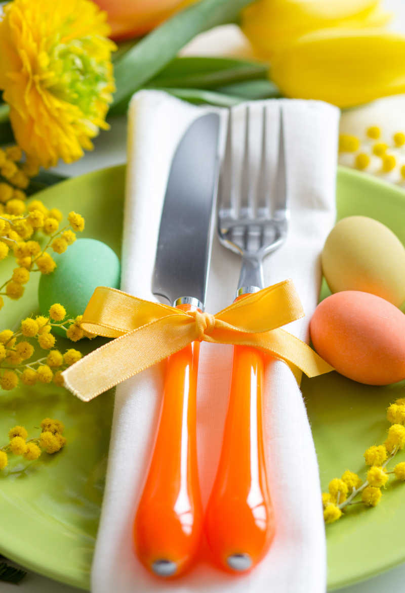 白色背景下的复活节餐桌上的餐具彩蛋和黄色花儿