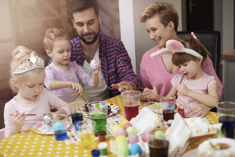 一家人坐在桌前一起制作复活节彩蛋