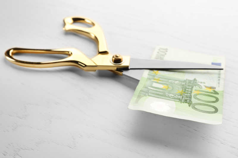 剪刀在剪欧元钞票在桌子上