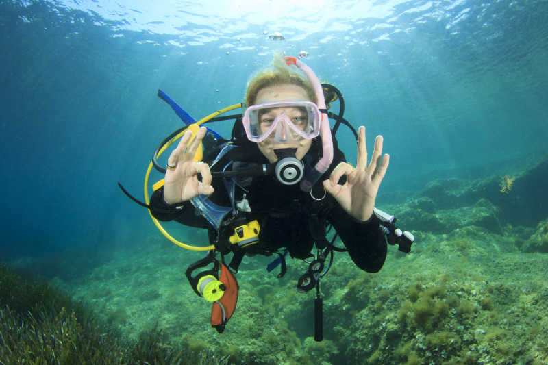年轻女子潜水员在海底发出OK的信号