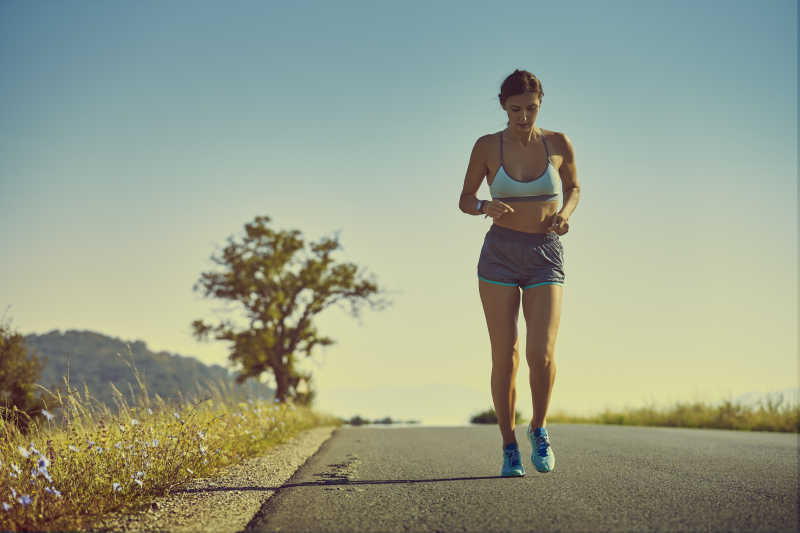 穿着运动短裤在公路上慢跑的女孩
