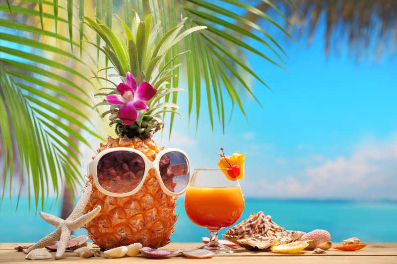 异国风情的沙滩上与一杯果汁与菠萝上的太阳镜
