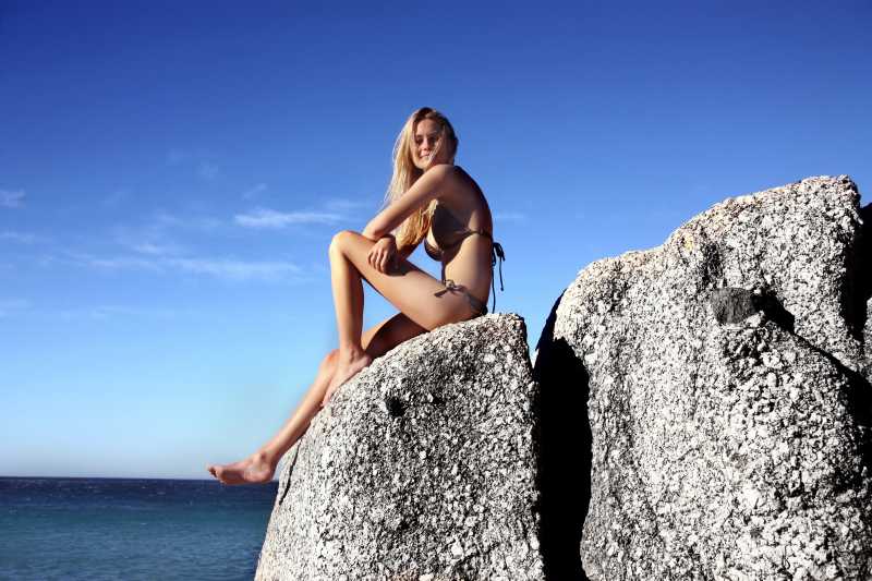 坐在岩石上的比基尼美女