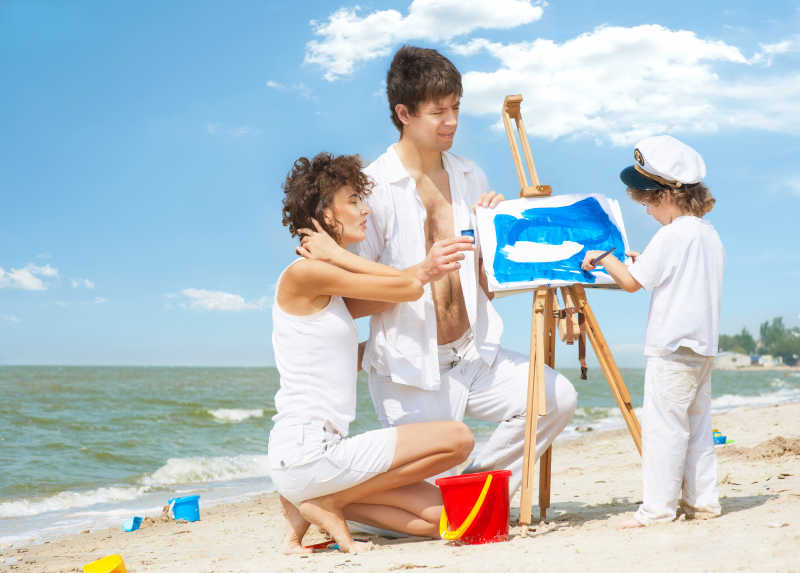 沙滩上父母看孩子画画