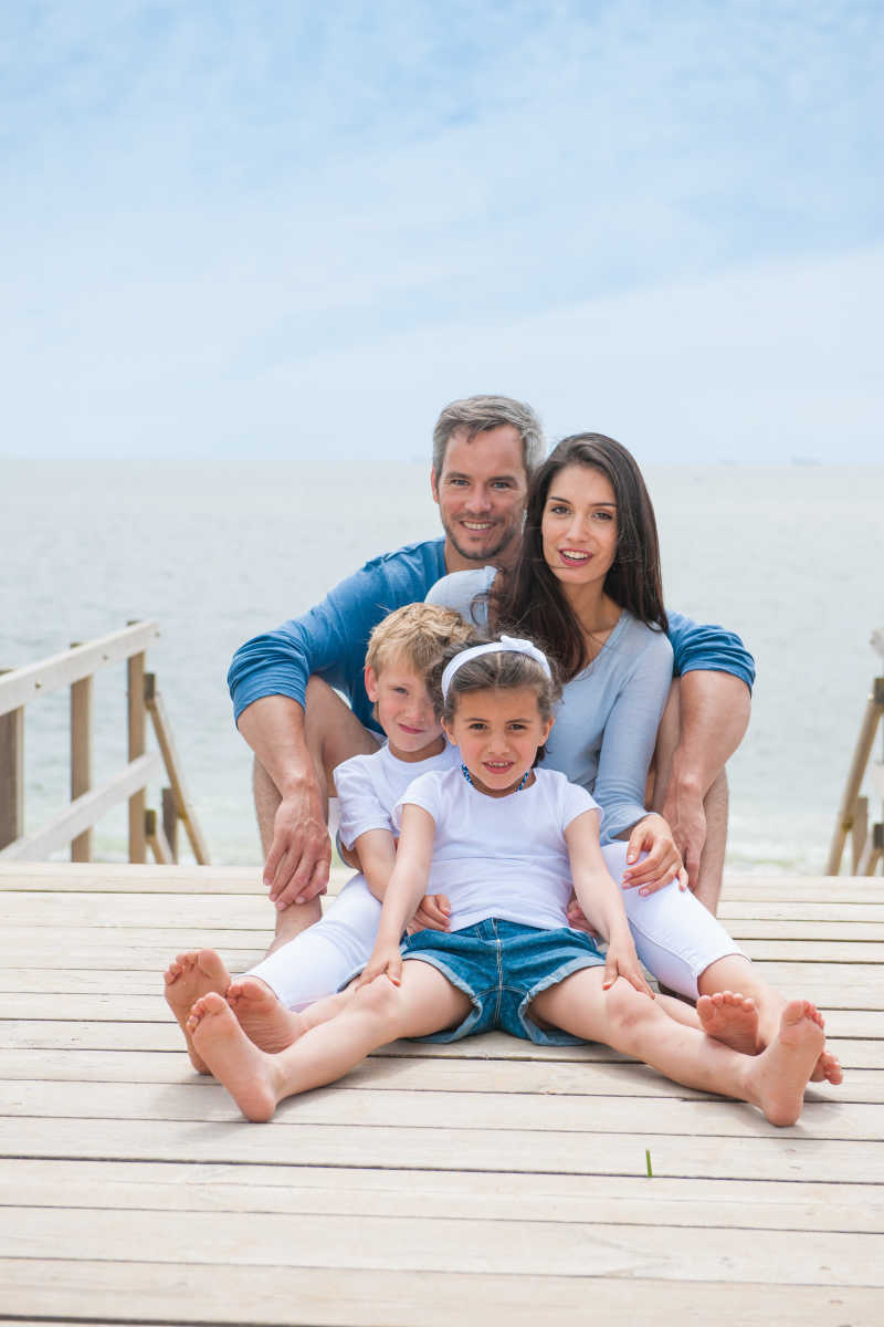 幸福的家庭坐在海边的木制浮桥上
