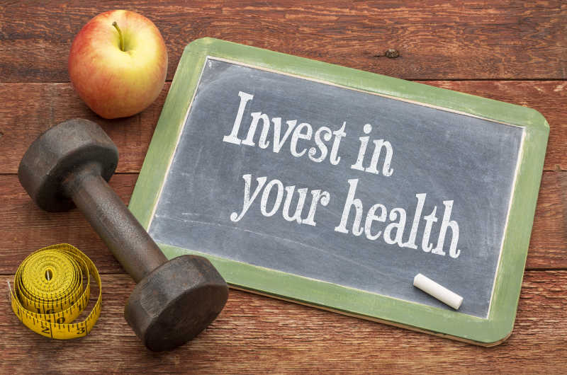木板上的哑铃苹果和卷尺以及投资你的健康石板黑板符号