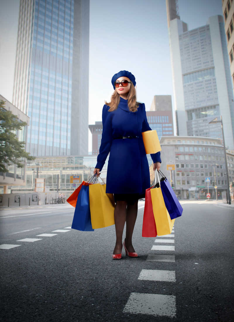 在城市街道上拎着购物袋的时尚女士