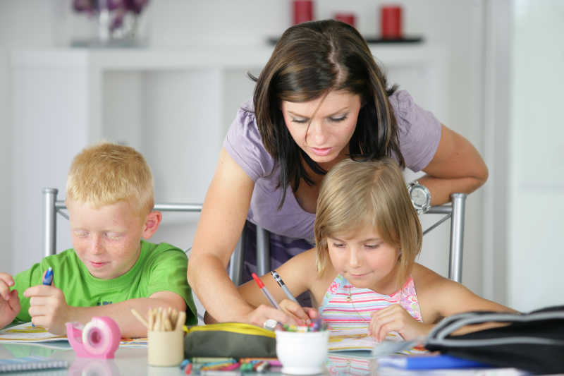 帮助孩子们做家庭作业的年轻母亲