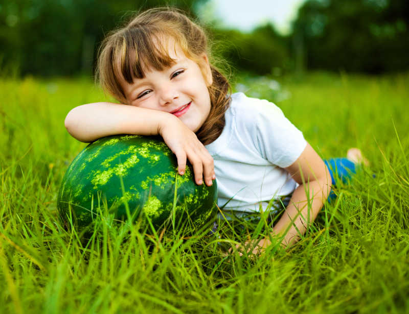 草地上抱着一个大西瓜的小女孩