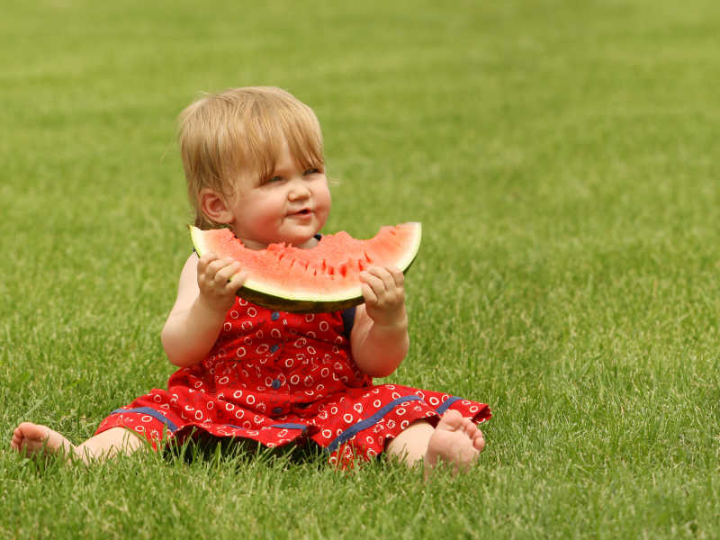 可爱的在草地上吃西瓜的小宝宝
