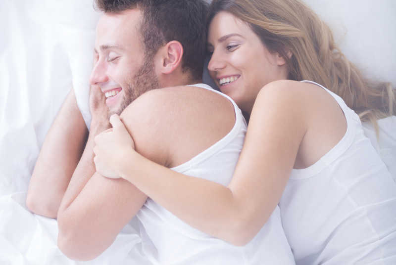在床上亲热拥抱的年轻夫妇