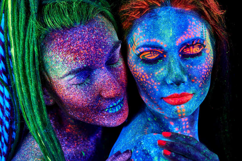 两位身上涂满彩色荧光粉的女性