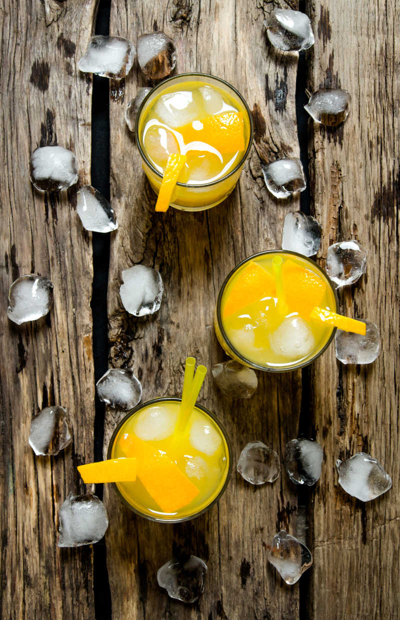 木制桌面上的三杯新鲜橙子汁