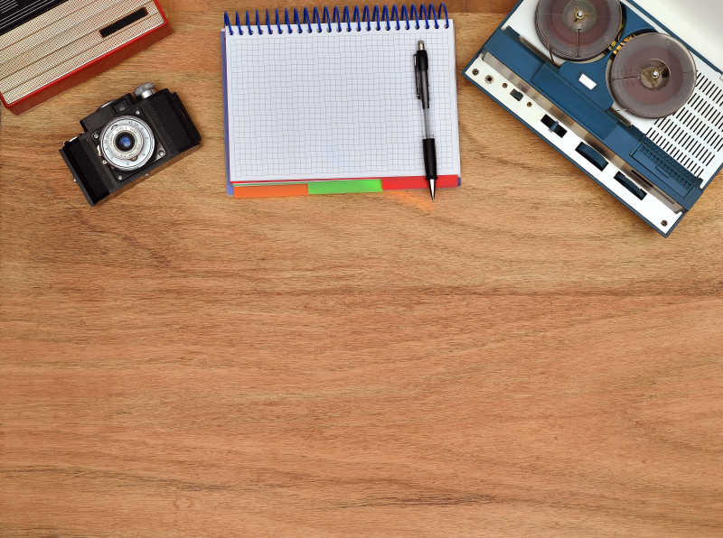 木桌上的复古收音机相机和笔记本