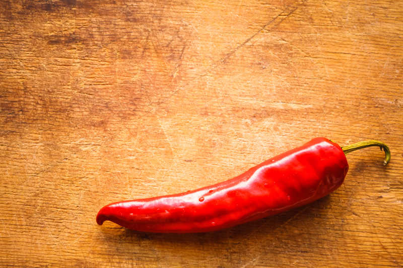 旧木桌上的一个红辣椒