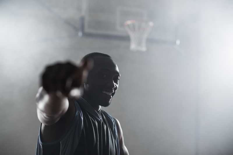 篮球架背景前的篮球运动员手指着镜头