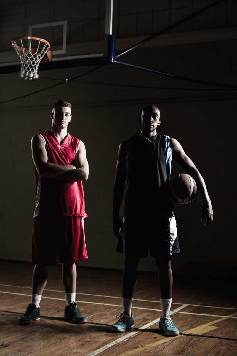 站在篮框下的两位篮球运动员手拿篮球