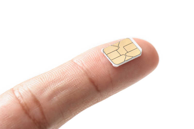 白色背景下食指上的微小的SIM卡