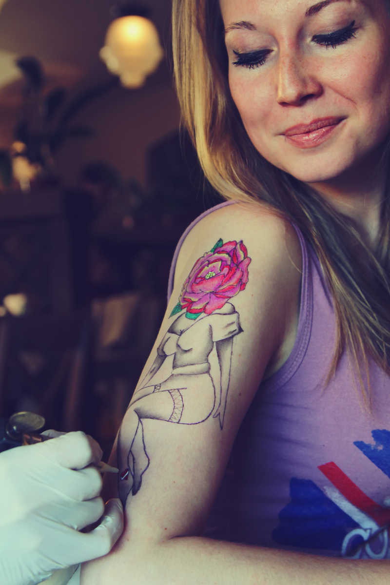 纹身师正在给女孩的手臂绘制纹身