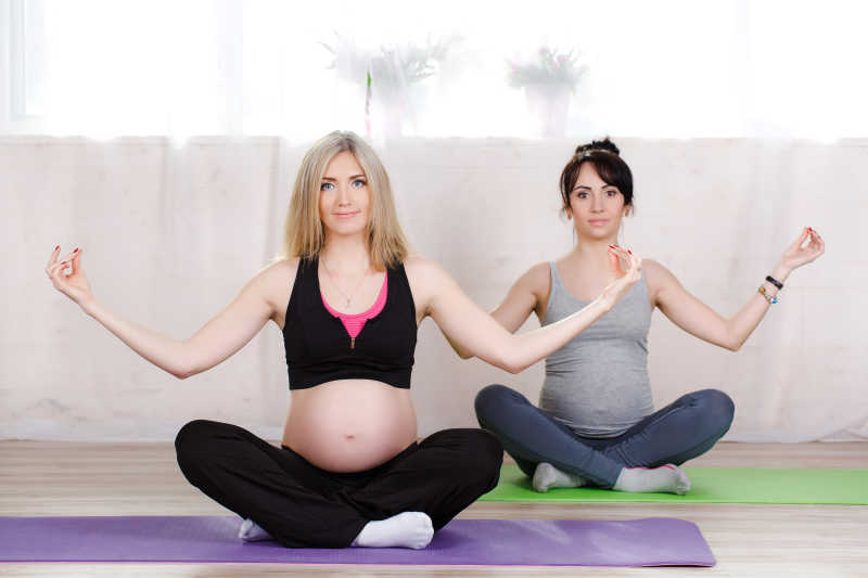 坐在瑜伽垫上练习瑜伽的孕妇
